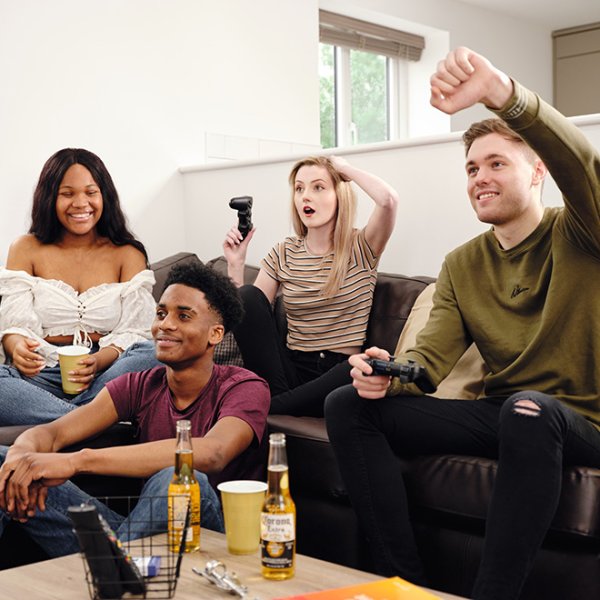 Four students laughing and playing video games together in a modern Luxury Student Homes student accommodation lounge